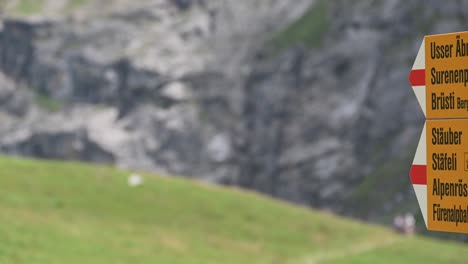 Schilder-Am-Berg-Weisen-Auf-Den-Wanderweg-Hin,-Dann-Blick-Auf-Einen-Felsigen-Berg,-Engelberg,-Obwalden,-Schweiz