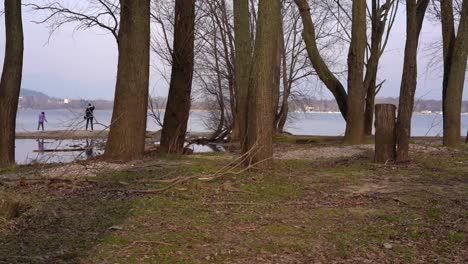 mother and child seen walking through trees on lakeside