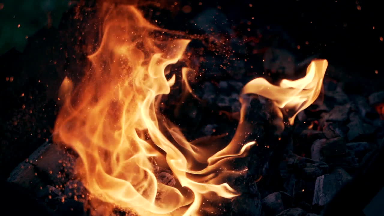 Bonfire. Burning logs in orange flames. Beautiful fire burns brightly. Embers of the fire climb up. Slow motion