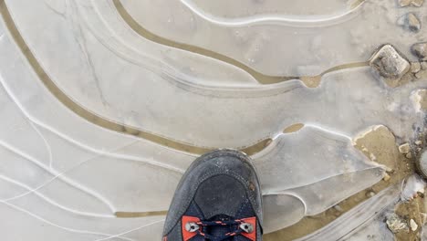 close up pov tiro de pisar un charco congelado con la bota de caminar y romper el hielo