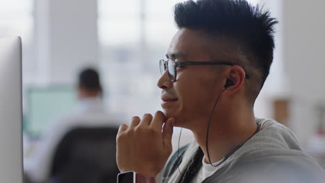 young asian businessman student using computer brainstorming problem solving idea looking pensive thinking of solution in office workplace wearing earphones