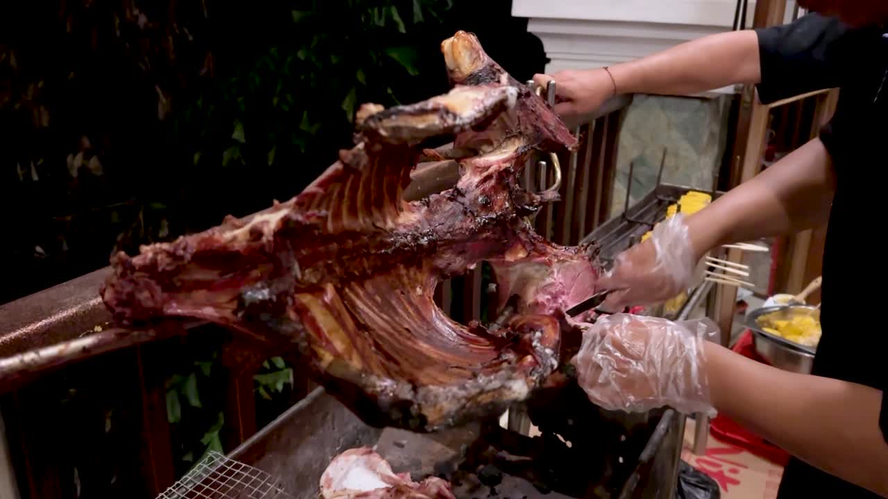 셰프는 김으로 구운 염소 고기를 칼로 잘라내고 있습니다.