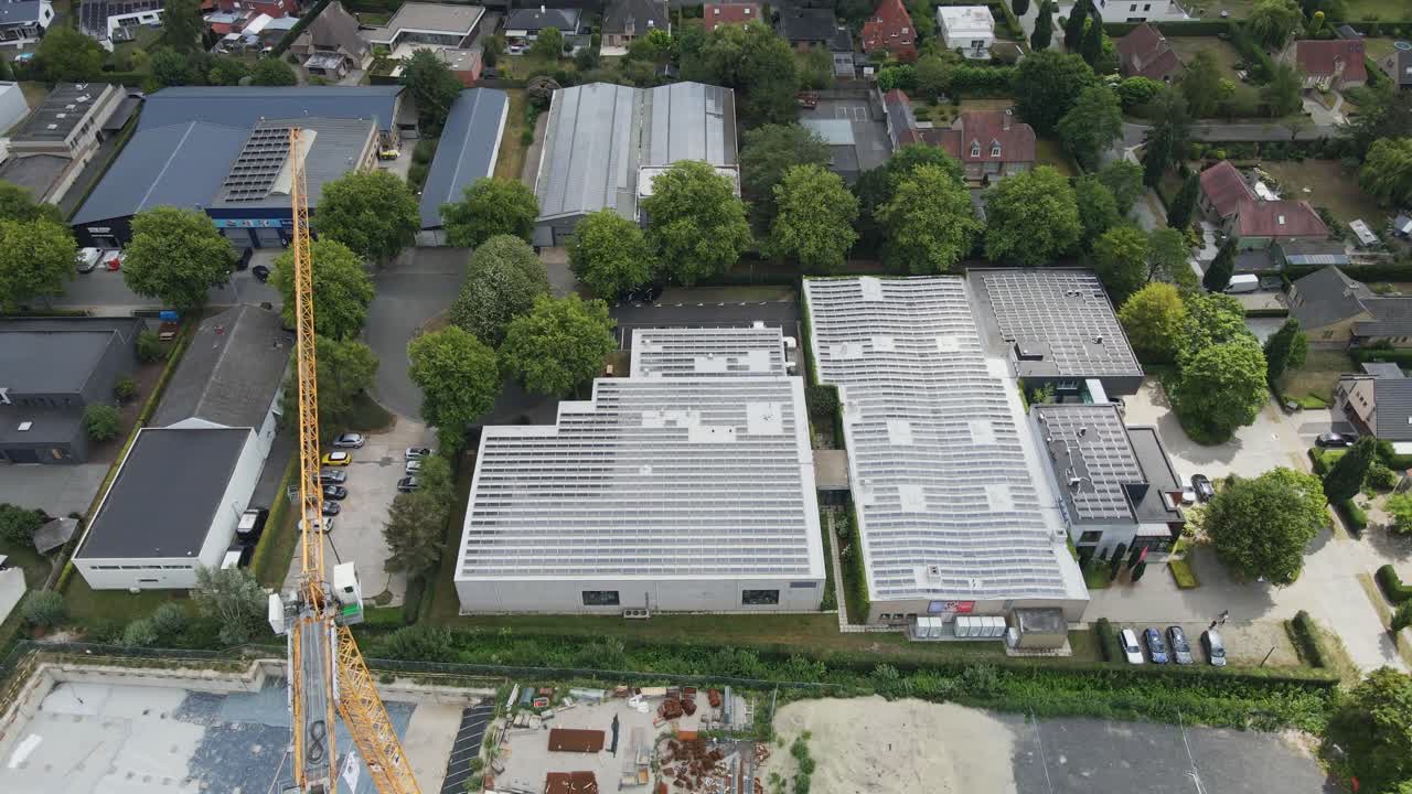 Beautiful aerial orbit of photovoltaic solar panels on thee rooftops of newly built industrial building on a sunny day
