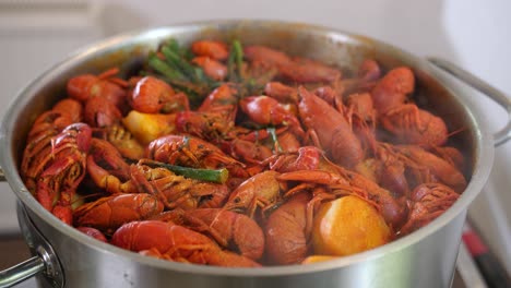 fresh seafood red crayfish shrimps prawn slowly boiling in a steel pot, warm tasty smoky soup recipe cooked in professional kitchen