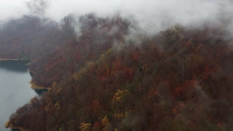 Aerial-rotates-over-mountain-Lake-with-autumn-leaves-in-rain-clouds