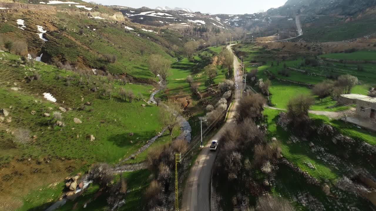 Inseguimento aereo di un'auto che percorre una strada di campagna in un paesaggio suggestivo
