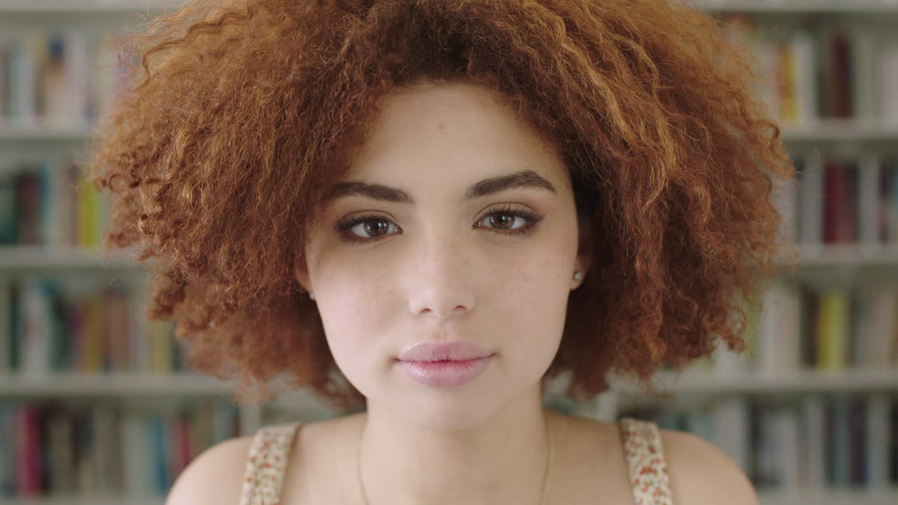 retrato de una mujer joven estudiante sonriendo estantería biblioteca universidad