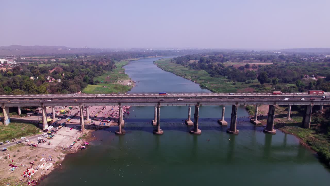 narmada river with greenery, haze and bridge at day time, push in, tilt down, drone shot, 4k.
