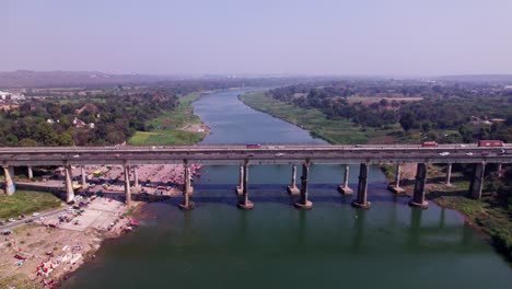 narmada river with greenery, haze and bridge at day time, push in, tilt down, drone shot, 4k.