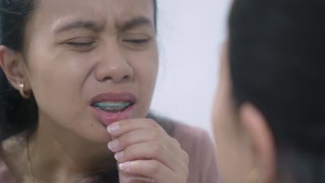 woman with braces looking at her teeth in a mirror