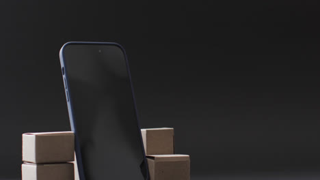 Video-of-smartphone-with-blank-screen-and-boxes-with-copy-space-on-black-background