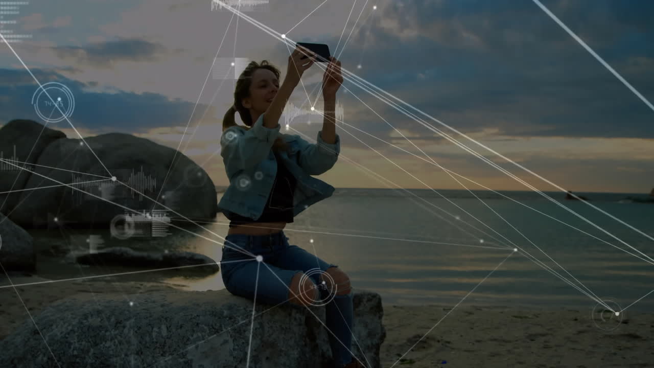 Woman sitting on rock by sea with digital network animation overlay