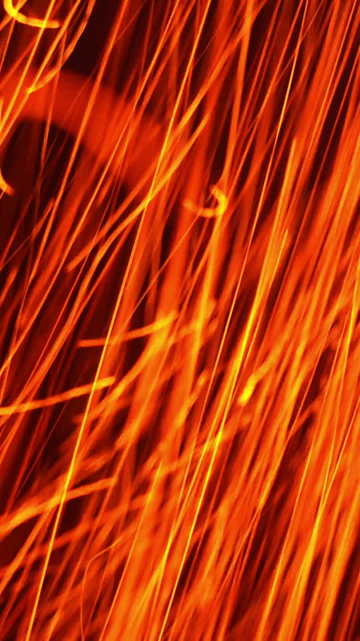 Quick orange scintilla flying vertically down. Hot particles at a fast speed at black background. Close up. Vertical video