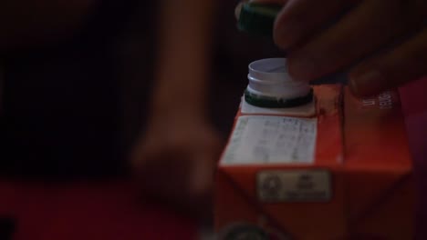 hands slowly opened the plastic lid of a ready to drink fruit beverage pack in agra city, india. - close up shot