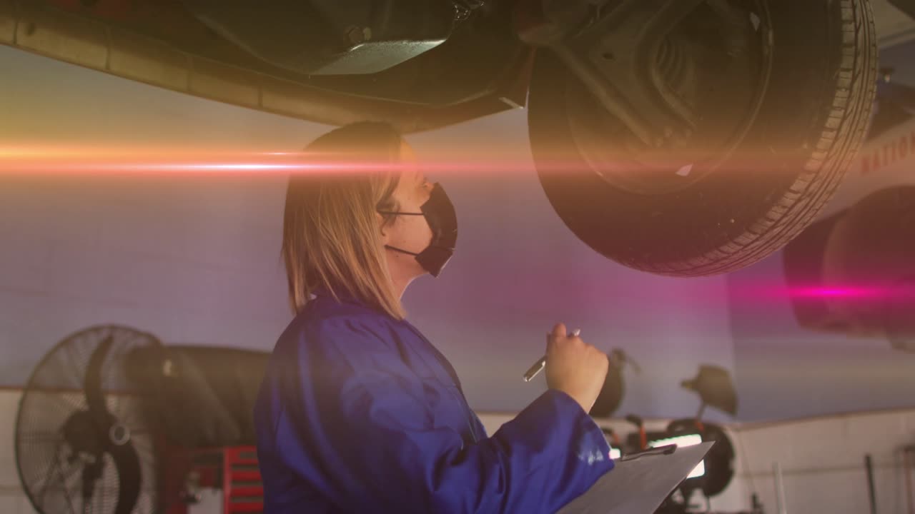 Automotive technician pausing notes then inspecting raised tire, animated overlay measuring tread