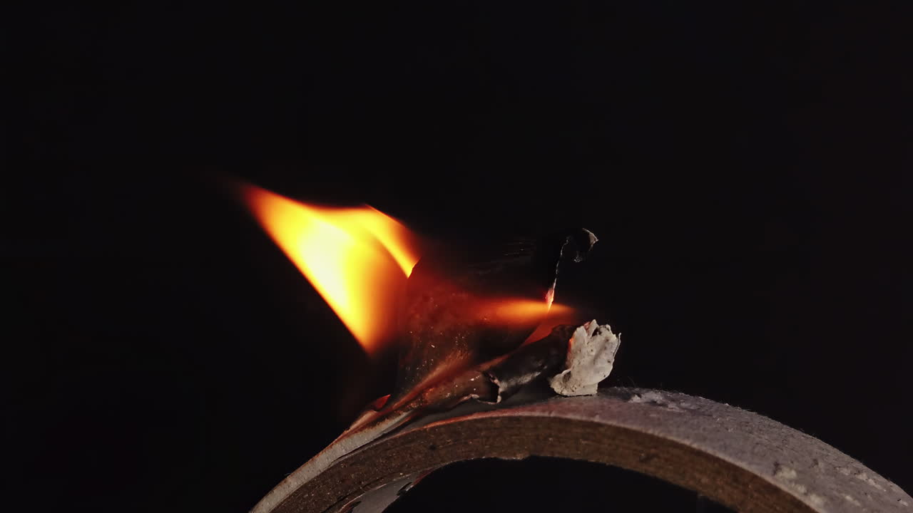 Wax on the stick burning in front of a black background. Ecology idea. Close up. Slow motion shot