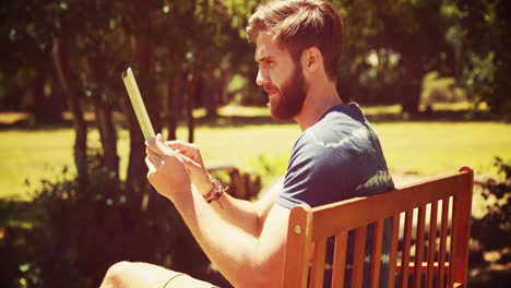 en formato 4k de alta calidad joven usando una tableta en un banco del parque