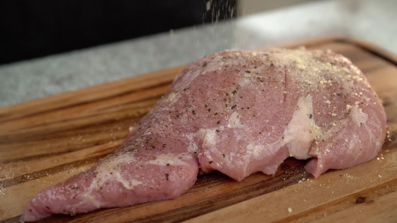 primer plano de un chef agregando cebolla en polvo a un bistec de carne cruda, cámara lenta