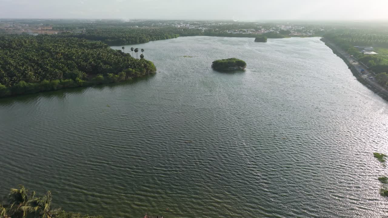 Cinematic aerial view of Samalapuram Lake, showcasing rippling waters, tiny green islands, and lush surroundings. A scenic blend of nature’s calm beauty with a vast, serene, and picturesque landscape