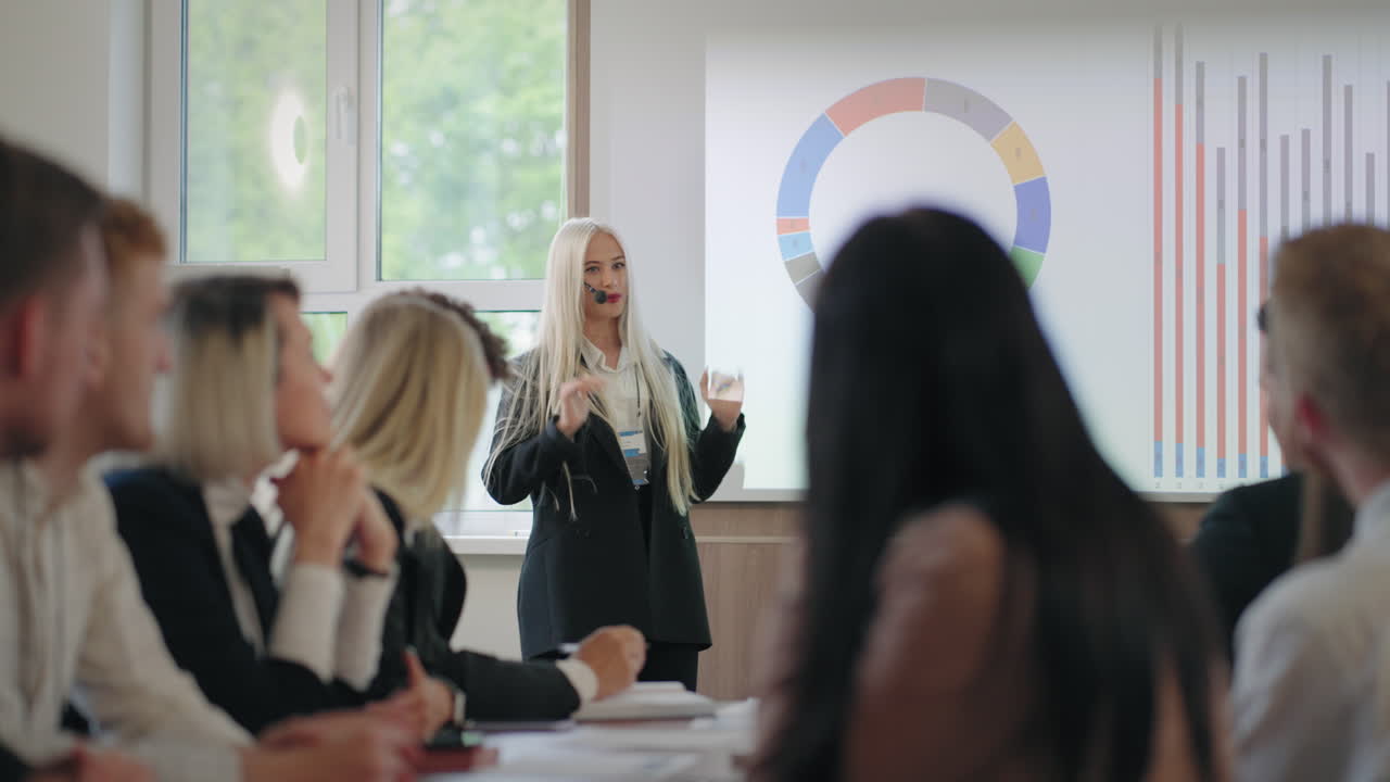 donna eccitata sta parlando per i colleghi e partner in una conferenza aziendale dimostrando grafici