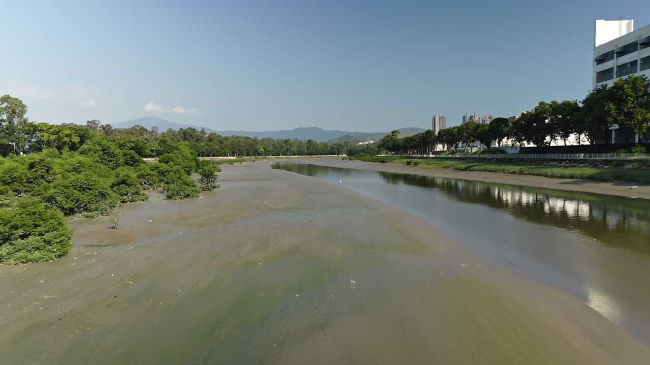 Low drone flight over marsh area on Shan Pui river near a factory, Hong Kong