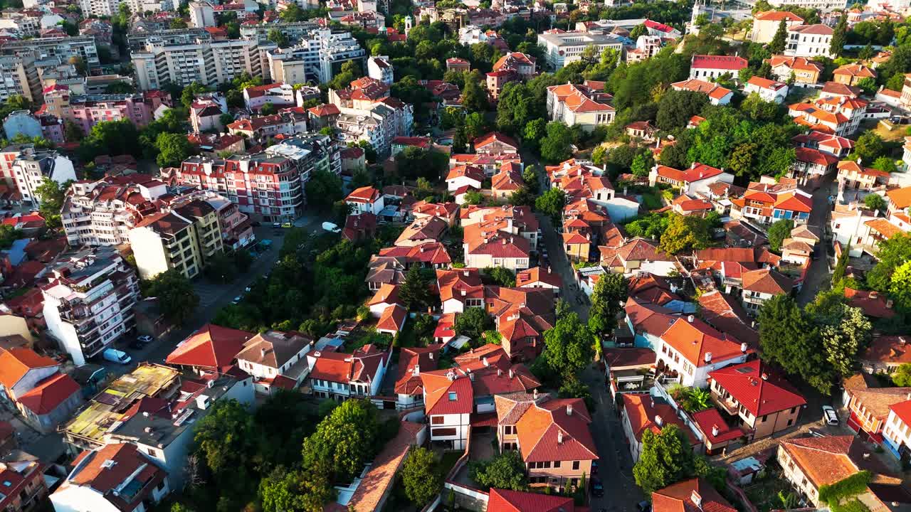 Drone pushes over vibrant Plovdiv neighborhoods with terracotta rooftops and lush greenery bathed in warm golden light