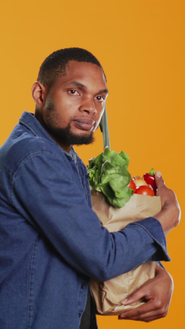 Homem divertido segurando sacola de compras com vegetais frescos