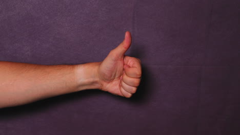 male hand shows fist and thumbs up on black background behind all capture in 120fps slow motion movement from one side to middle