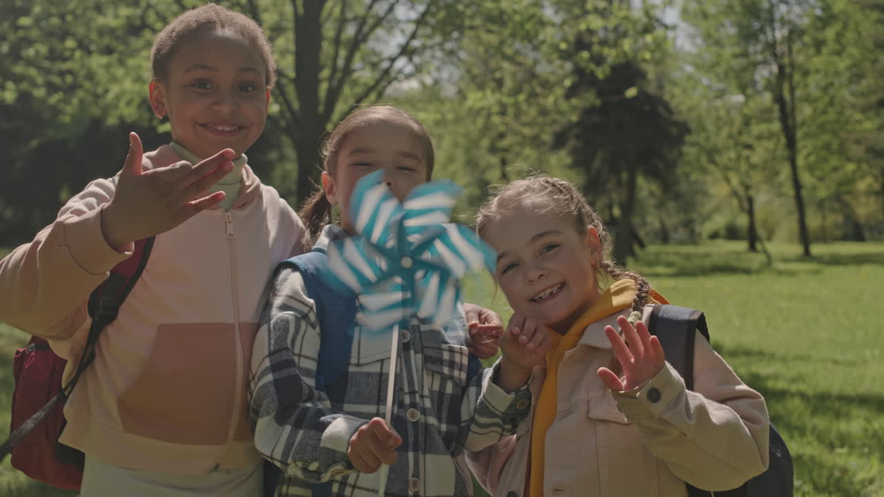 Three young girls playing with a pinwheel in the park