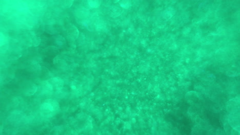 green water with bubbles and sparkles runs at bright light