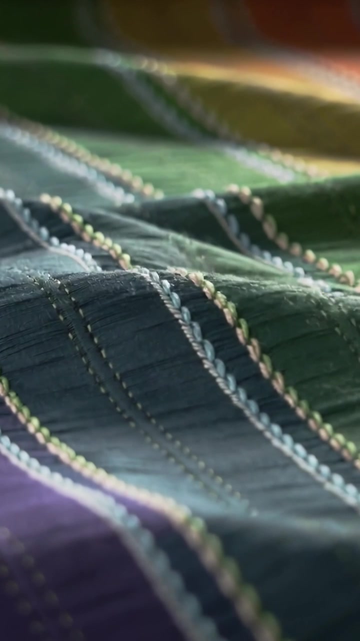 Vertical video: Moving camera revealing quilted panel in room, showing braided trim and stitching