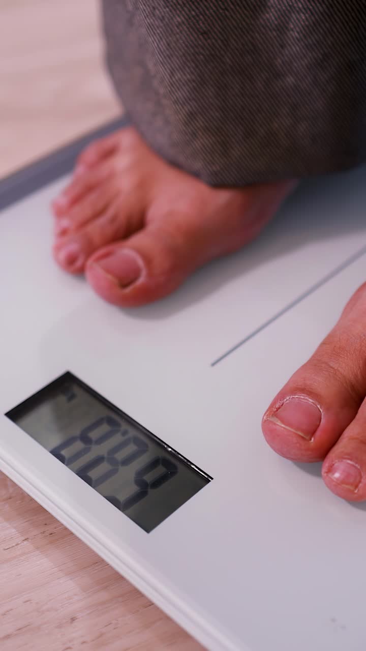 Close-up shot of bare feet stepping on a digital scale to check body weight