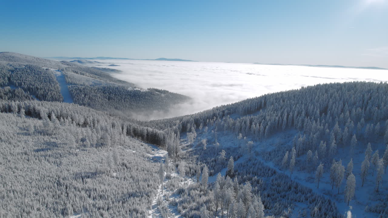 zdjęcie krajobrazu z lotu ptaka przedstawiające wzgórza i góry pokryte świeżym śniegiem zimą z chmurą i mgłą w dolinie