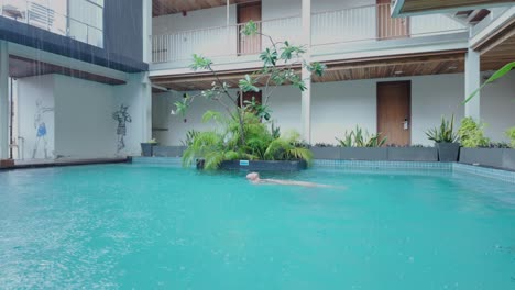 person swimming in a rain-filled hotel pool