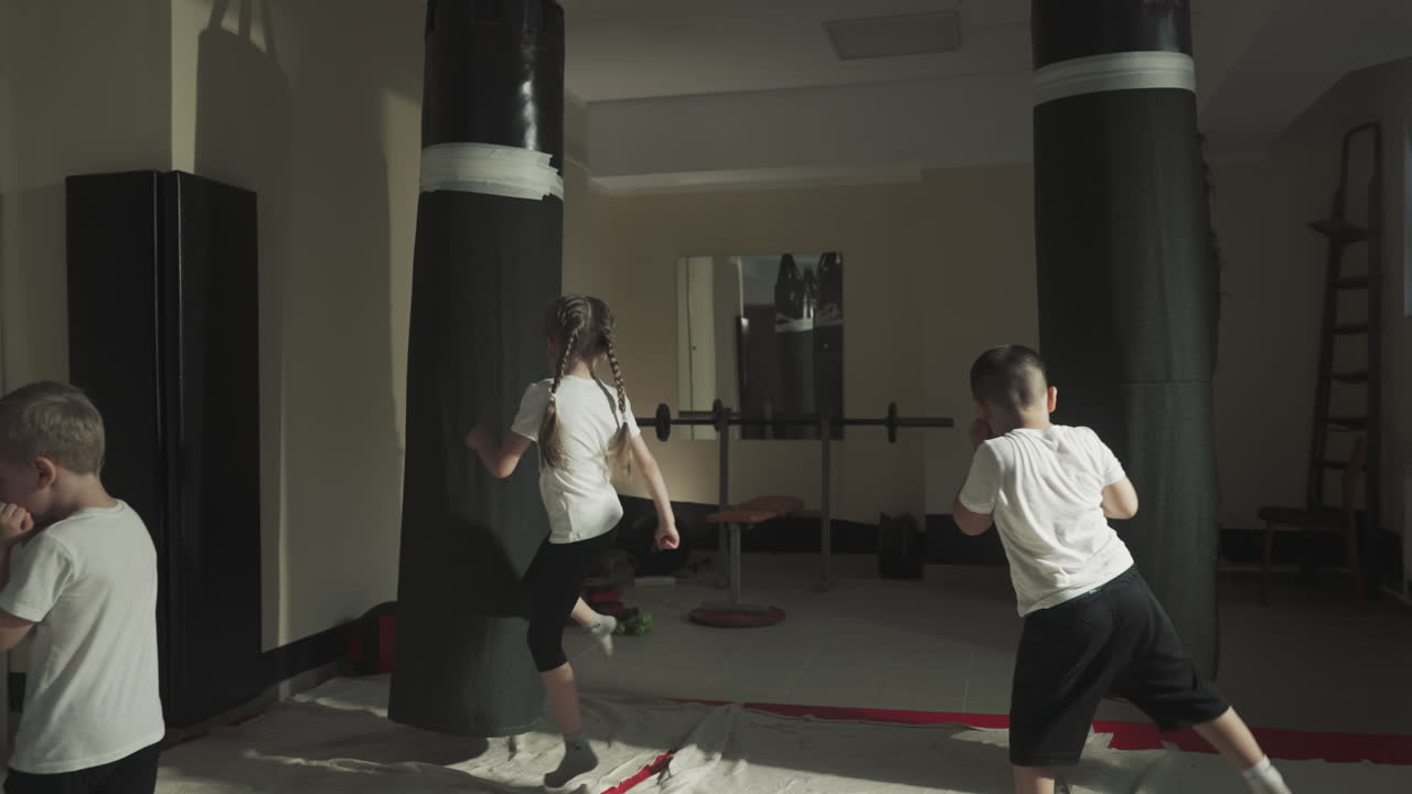 Kids and adult boxers do exercises in sports club. Little children learn kicks with professional sportsmen with fighting gym slow motion. Martial arts