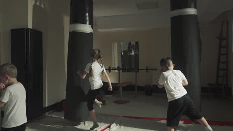 kids and adult boxers do exercises in sports club. little children learn kicks with professional sportsmen with fighting gym slow motion. martial arts