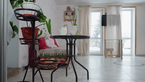 cozy modern room decorated with green plants, chair, television, flowing curtain and natural light reflecting on tiled floor and brick wall, creating bright airy ambience ideal for indoor greenery