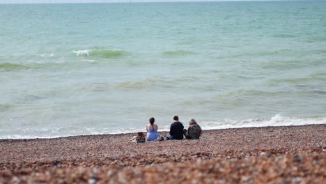 two people sitting on a pebbled beach