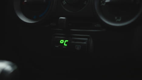 close up of car dashboard climate control digital temperature display showing 3.9 degrees with dials and buttons in blurred background highlighting green led readout and cabin environment details