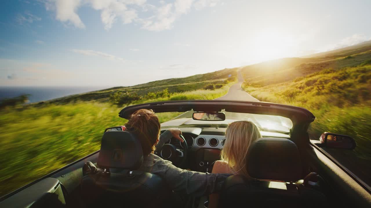 una pareja conduciendo hacia la puesta de sol.