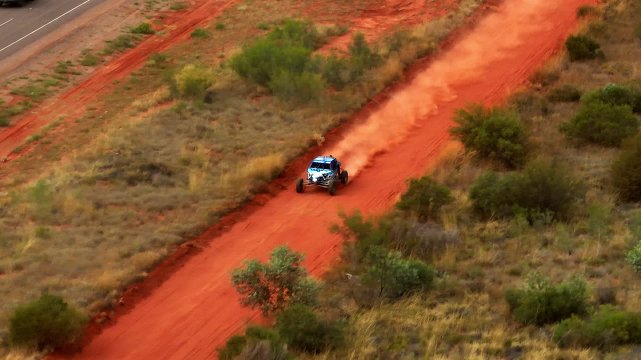 carreras de buggy fuera de carretera en la pista de tierra roja del interior a lo largo de la carretera rural en alice springs, australia, dron de teleobjetivo 4k