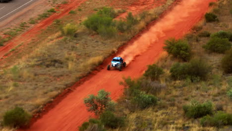 carreras de buggy fuera de carretera en la pista de tierra roja del interior a lo largo de la carretera rural en alice springs, australia, dron de teleobjetivo 4k
