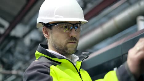 shot of professional factory worker wearing hard hat holds tablet computer, walking thorugh modern industrial manufacturing facility