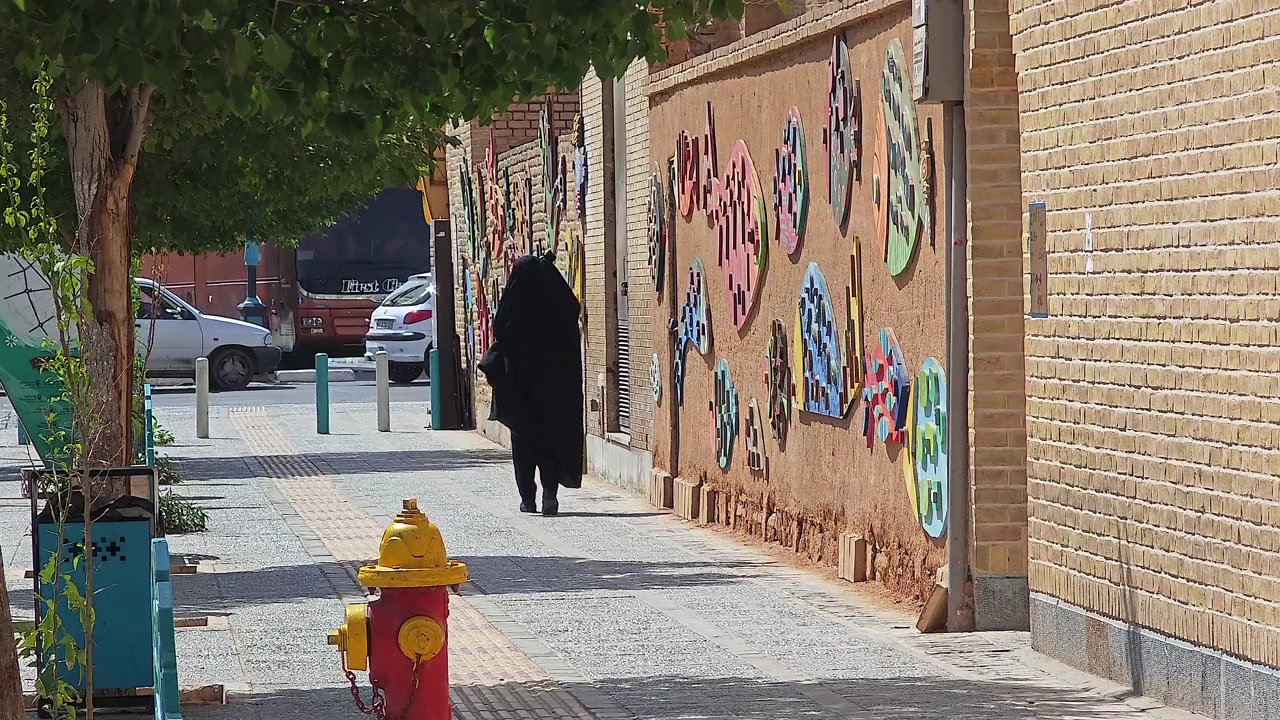 Donna in chador che cammina lungo un marciapiede urbano decorato