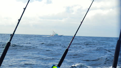 Boat-in-the-distance-with-a-fishing-pole-in-the-foreground,-Slow-motion