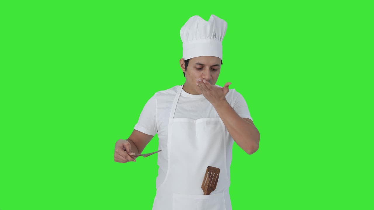 Felice chef professionista indiano che assaggia il cibo e fa il segno