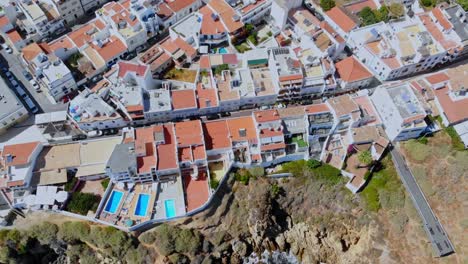 Drone-shot-filming-the-roofs-of-the-houses-by-the-coast-with-pools