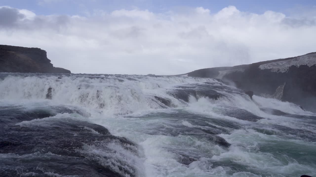 la majestuosa cascada de gullfoss en islandia con un spray de niebla y un cielo nublado