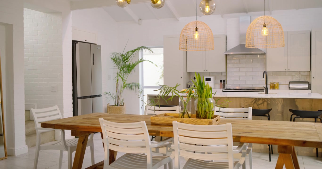 Al inicio, la cámara hace un paneo y zoom para revelar una mesa de comedor con sillas y una maceta en la cocina.