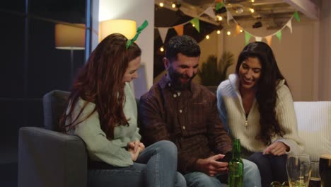 group of friends dressing up at home or in bar celebrating at st patrick's day party looking at photos on phone